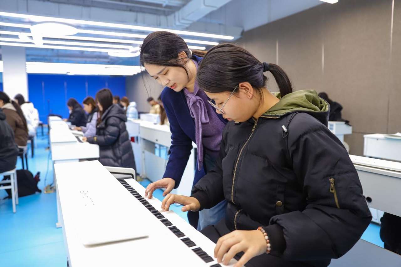 2025年12月24日，在山东青岛恒星科技学院未来教育学院实践教学基地，老师指导学生学习钢琴弹奏。张鹰 摄 (2)