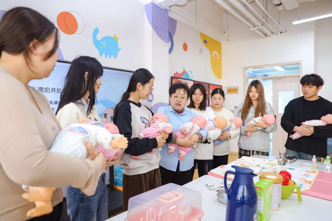 2025年12月24日，在山东青岛恒星科技学院未来教育学院实践教学基地，老师向学生演示新生儿日常照护技能。张鹰 摄 (2)
