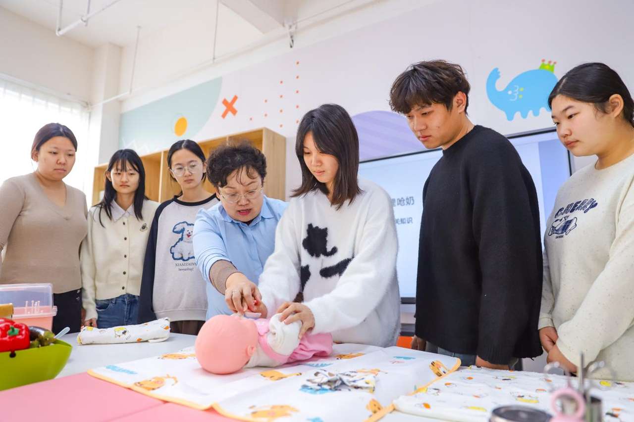 2025年12月24日，在山东青岛恒星科技学院未来教育学院实践教学基地，老师指导学生学习新生儿日常照护技能。张鹰 摄