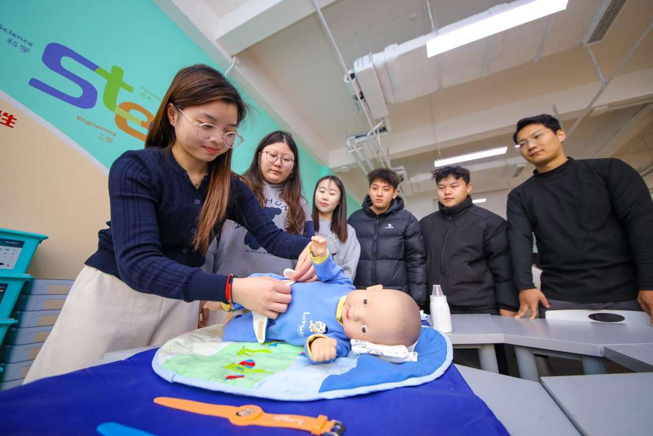 2025年12月24日，在山东青岛恒星科技学院未来教育学院实践教学基地，学生利用仿真新生儿练习日常照护技能。张鹰 摄